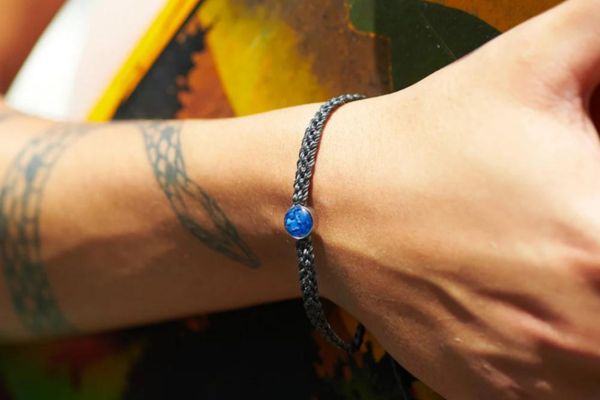 woman wearing a 4ocean braded ocean drop bracelet
