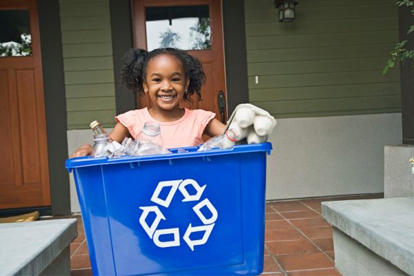 Young girl putting out the recycling bin