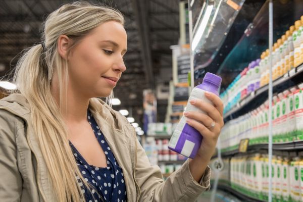 Young woman reads nutrition label on dairy product in supermarket